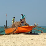 Fishermen load the boat with large net in preparation of fishing trip to the deep sea at Velsao Beach in Goa, India